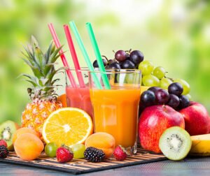 Fresh juice with fruits on wooden table with nature green background